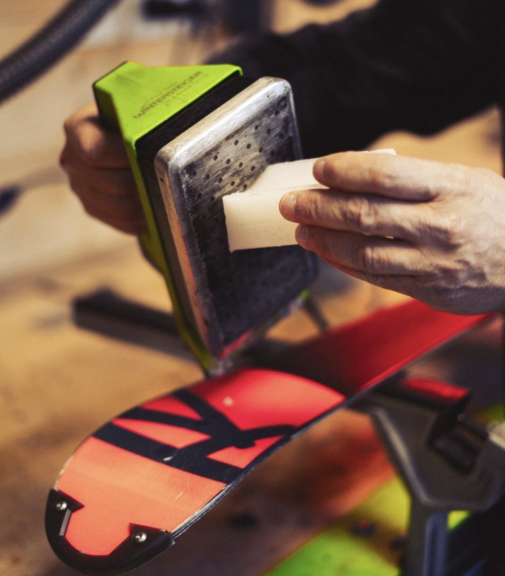 Block of white wax melting against the hot plate of a green waxing iron