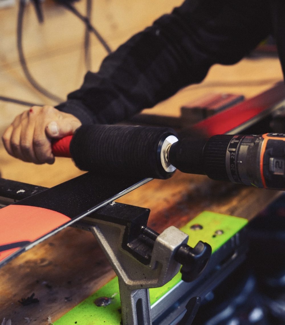 Rotary brush passed over the base of a black and orange ski