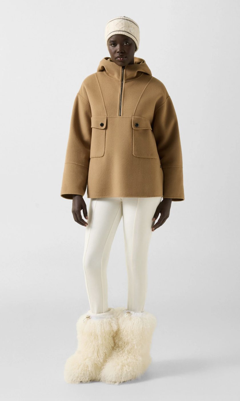 Veste à capuche en laine double face camel, portée avec un pantalon fuseau blanc