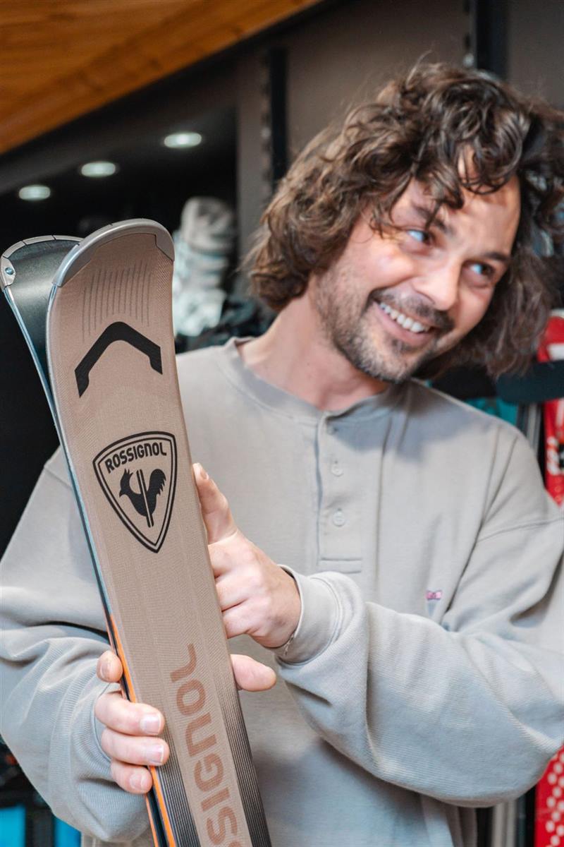 Lachende skitechnicus toont een paar Rossignol-ski's