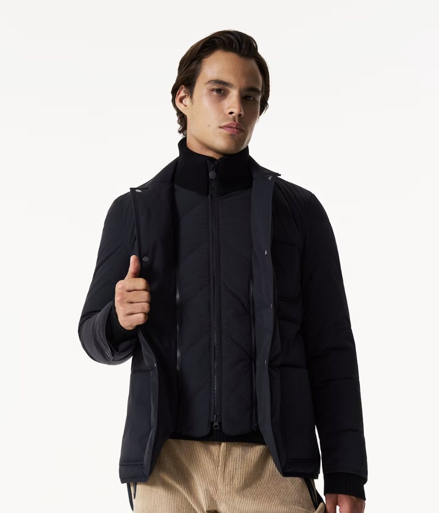 Veste matelassée noire à col montant, portée avec un pantalon en velours